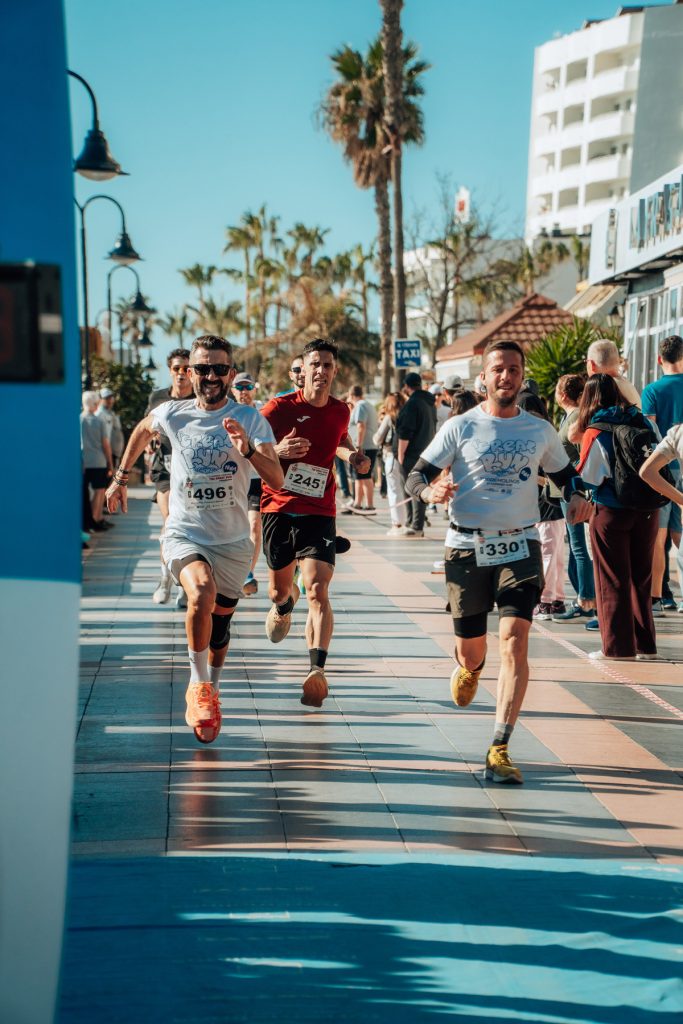 Corredores cruzando la meta de The Great Run La Carihuela en Torremolinos con el público animando