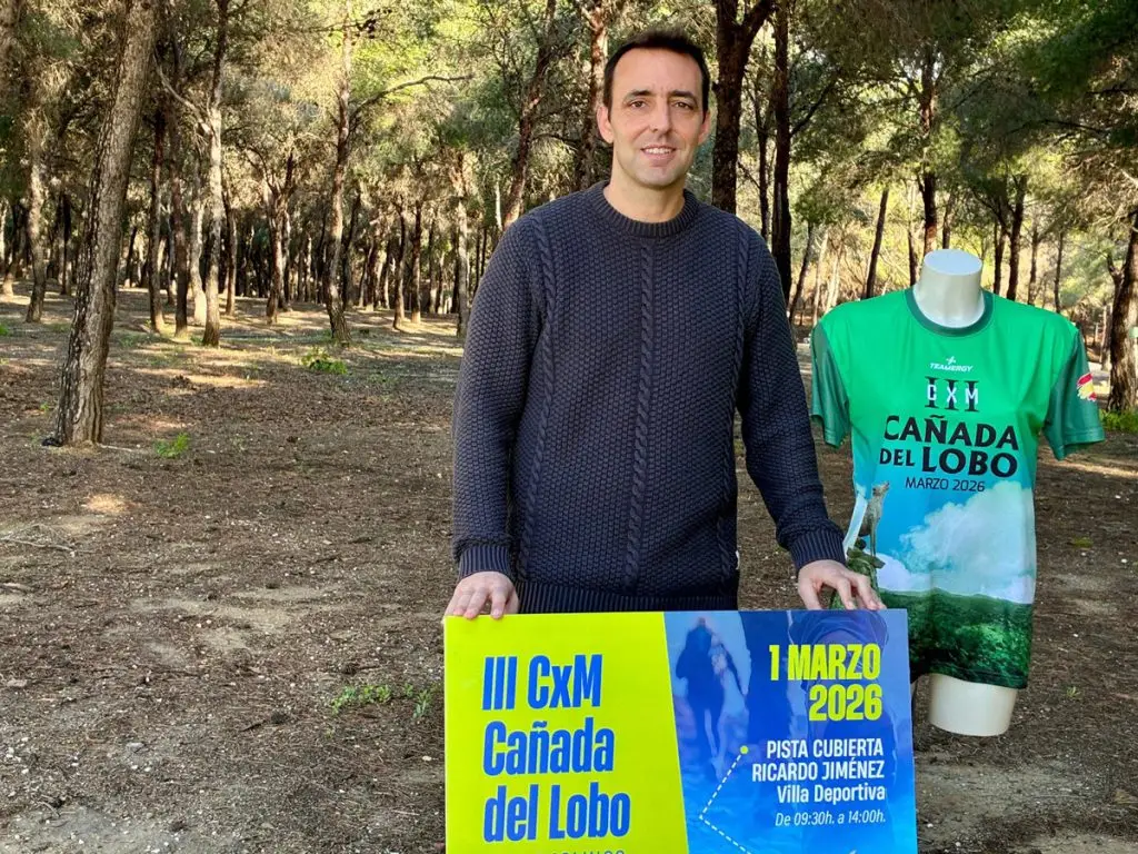 Concejal de Deportes de Torremolinos durante la presentación del III CxM Cañada del Lobo, junto al cartel de la prueba y la camiseta oficial en un entorno de pinar.