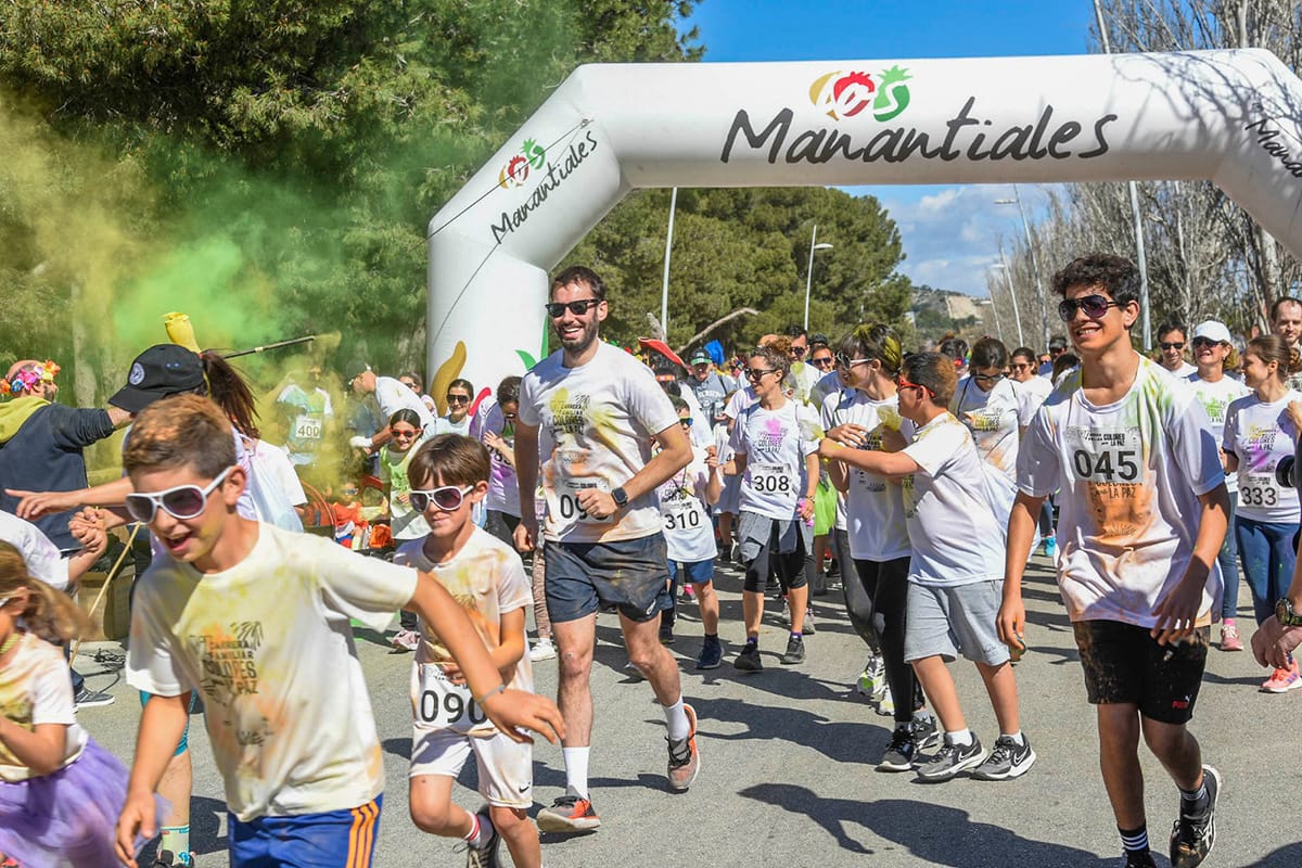 Salida de la Carrera Familiar Colores para la Paz en Torremolinos con participantes atravesando polvos de colores en el Paseo Marítimo de Los Álamos.